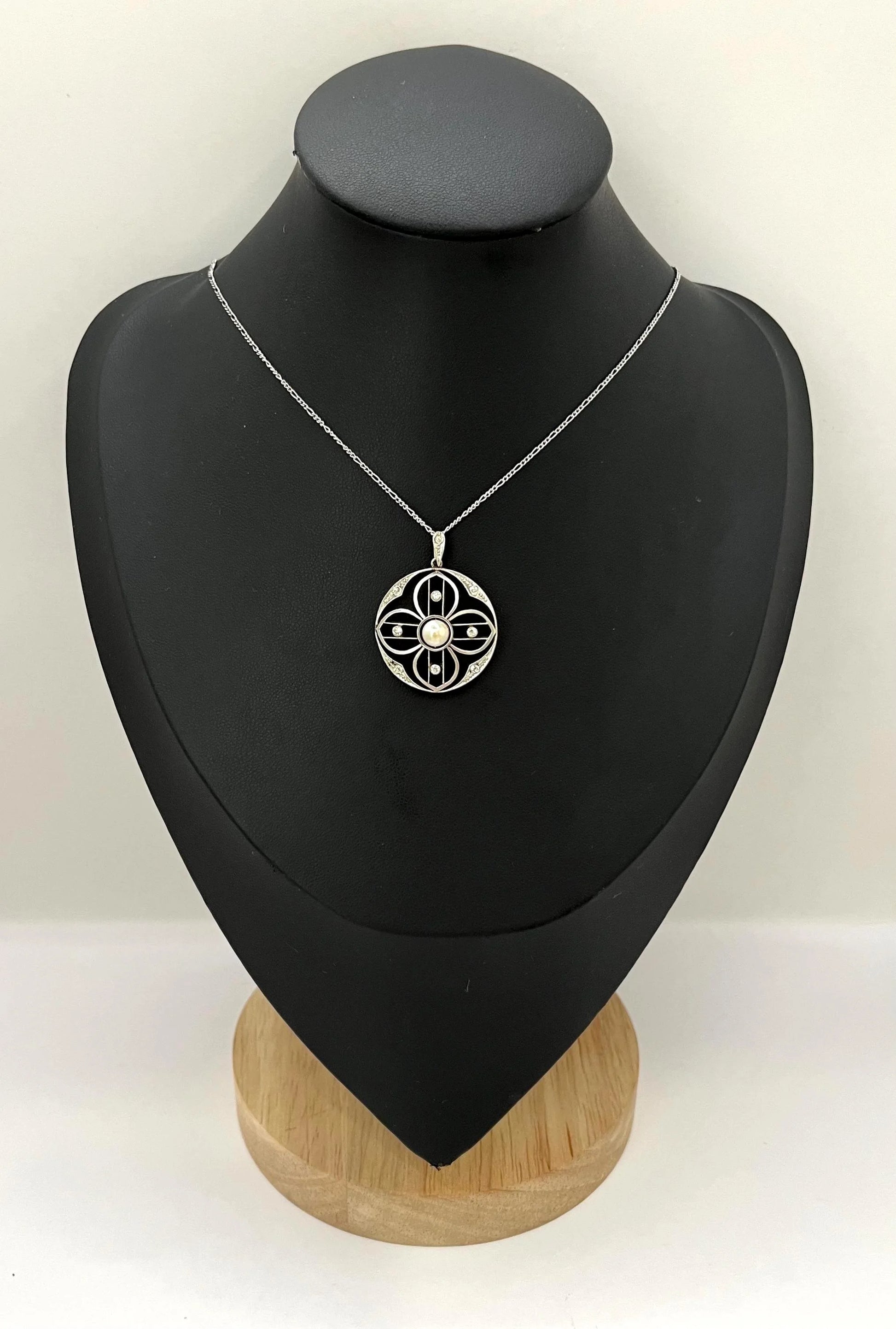 A circular openwork pendant with a pearl and diamonds, in yellow gold and platinum, with a chain, on a black bust