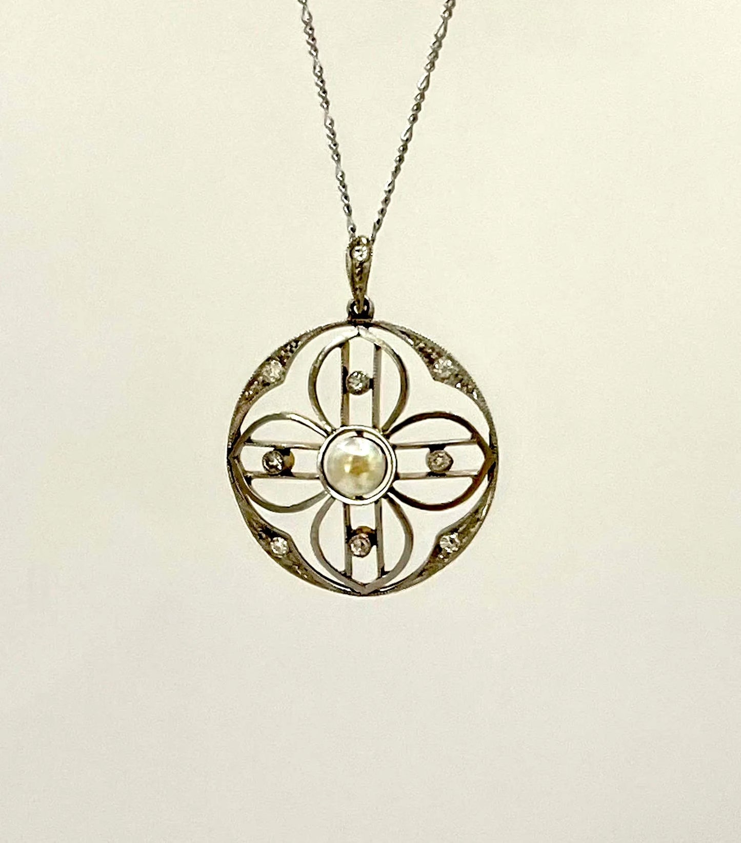 A circular openwork pendant with a pearl and diamonds, in yellow gold and platinum, with a chain
