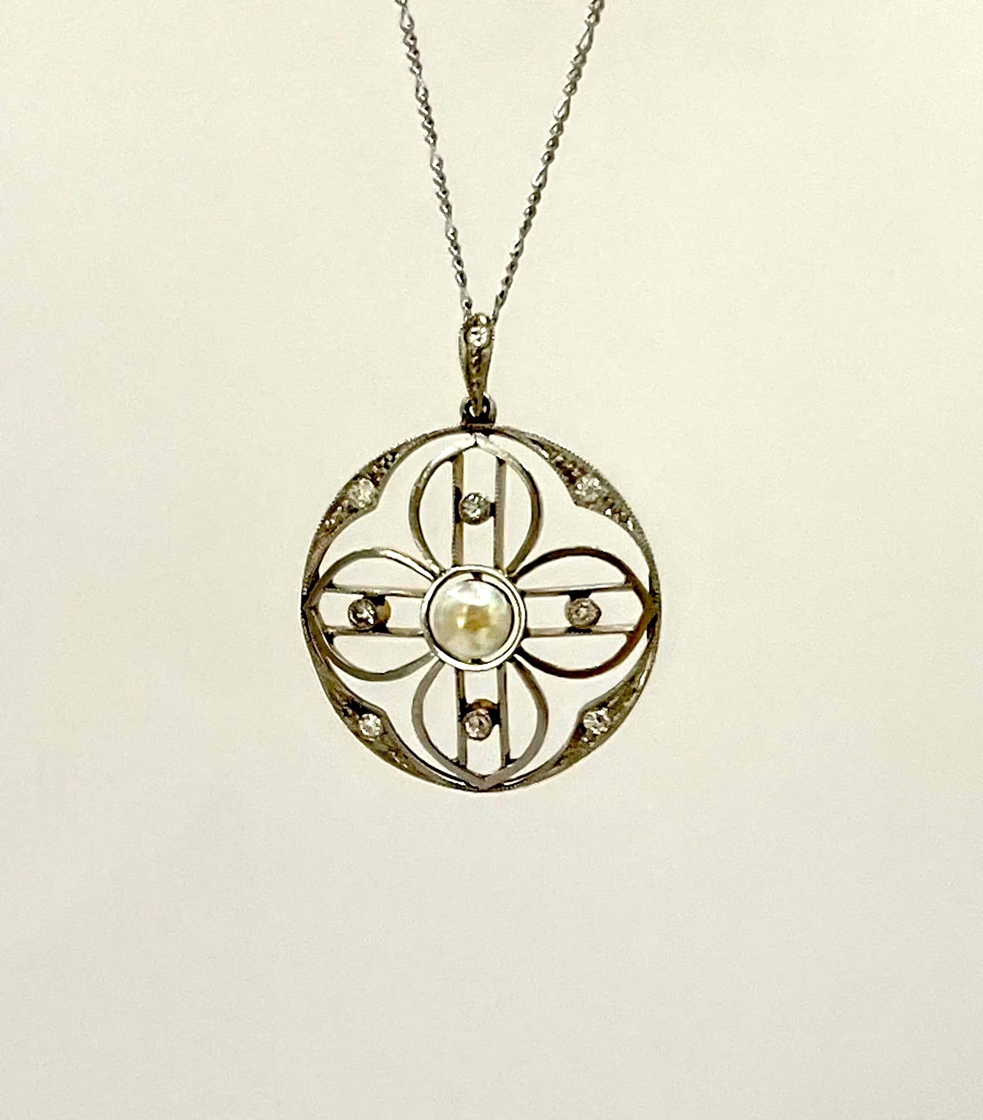A circular openwork pendant with a pearl and diamonds, in yellow gold and platinum, with a chain