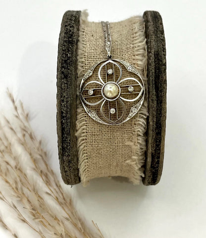 A circular openwork pendant with a pearl and diamonds, in yellow gold and platinum, with a chain