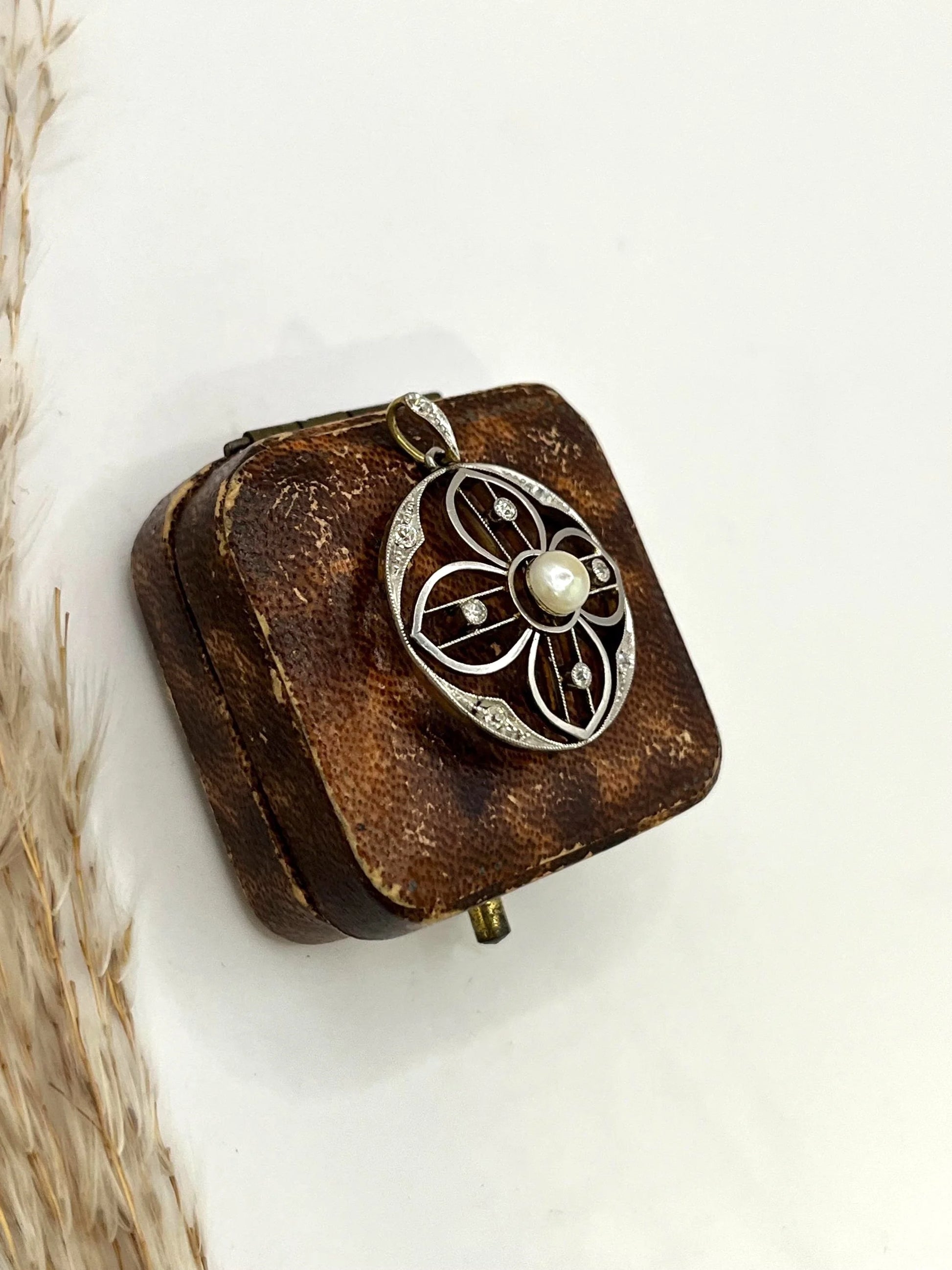 A circular openwork pendant with a pearl and diamonds, in yellow gold and platinum