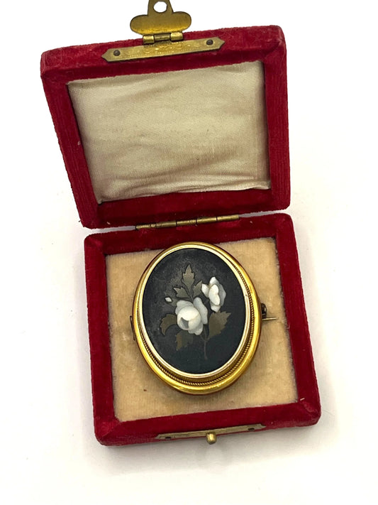 An oval pietra dura brooch displaying white flowers, mounted in yellow gold, in a box