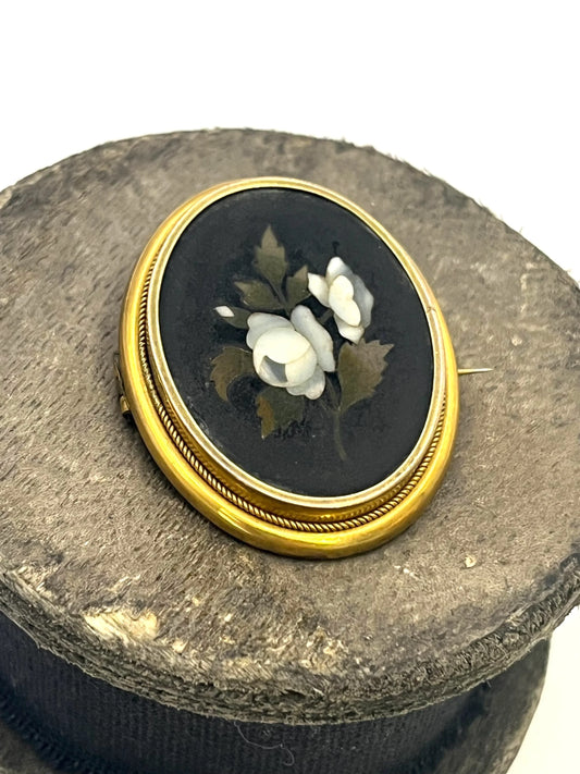 An oval pietra dura brooch displaying white flowers, mounted in yellow gold
