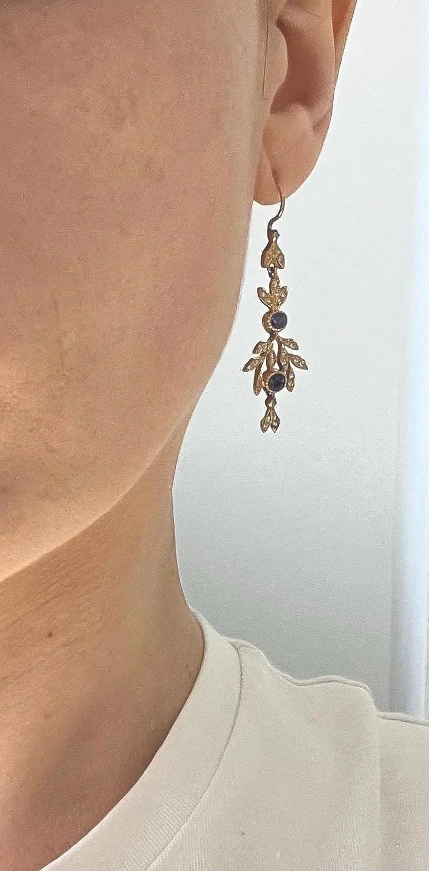 A sapphire and diamond foliate drop earring in yellow gold, modelled in an ear