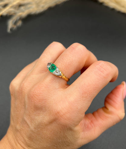 A three stone old cut emerald and diamond ring in yellow gold, modelled on a hand