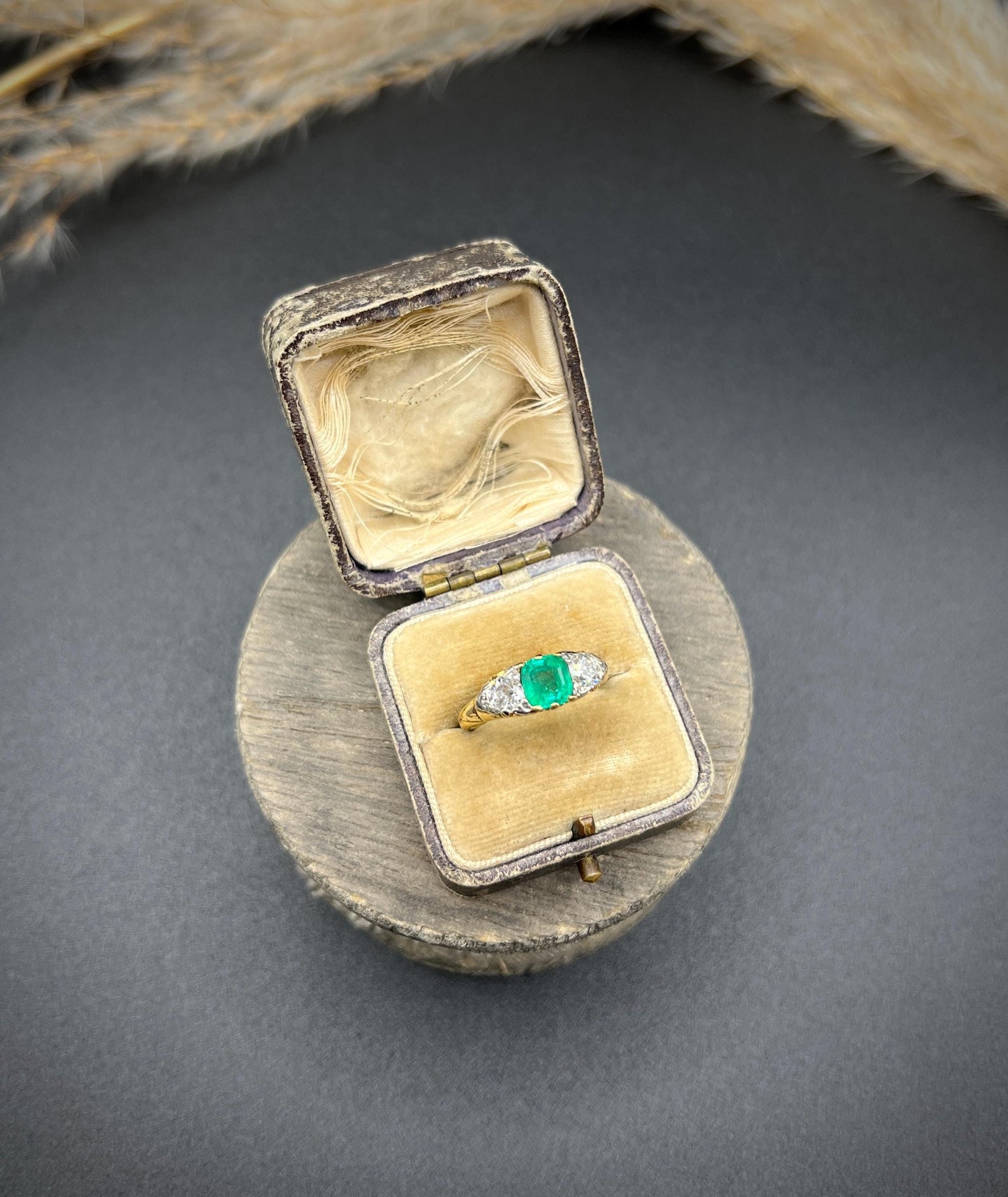 A three stone old cut emerald and diamond ring in yellow gold, in an antique ring box