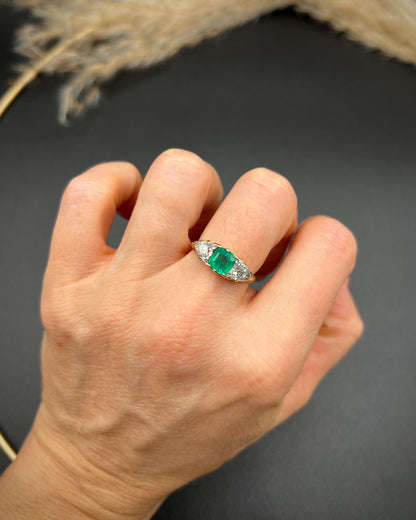 A three stone old cut emerald and diamond ring in yellow gold, modelled on a hand