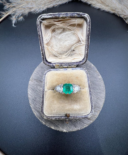 A three stone old cut emerald and diamond ring in yellow gold, in an antique ring box