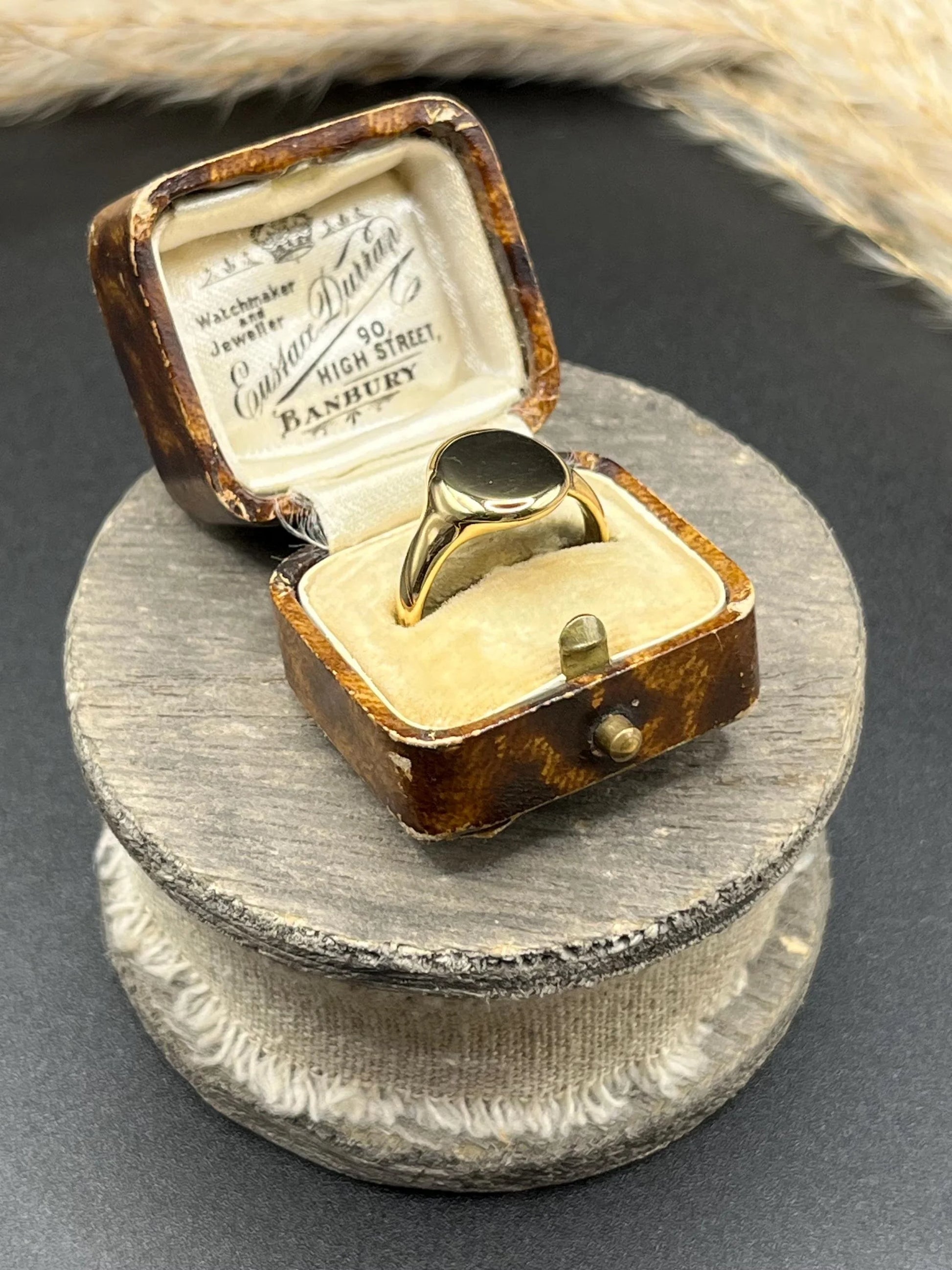 A yellow gold plain oval signet ring in a ring box