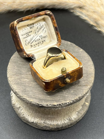 A yellow gold plain oval signet ring in a ring box