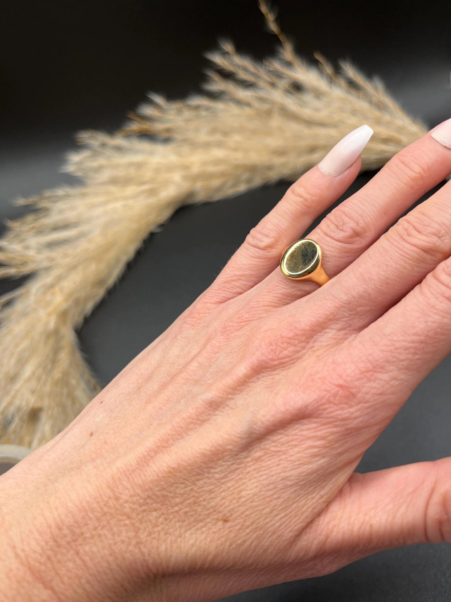 A yellow gold plain oval signet ring, modelled on a hand