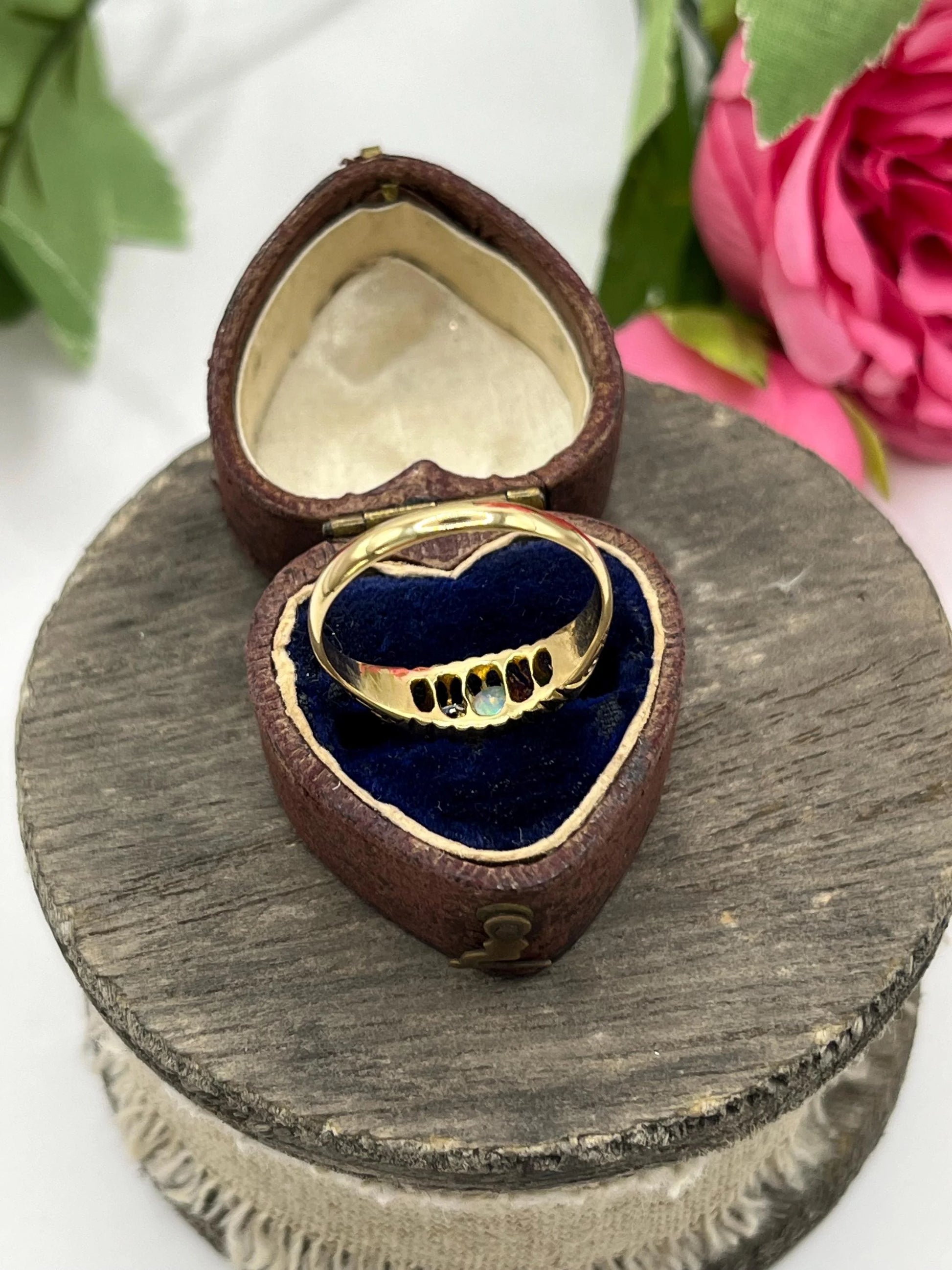 A five stone acrostic ADORE ring in yellow gold, in a heart-shaped ring box