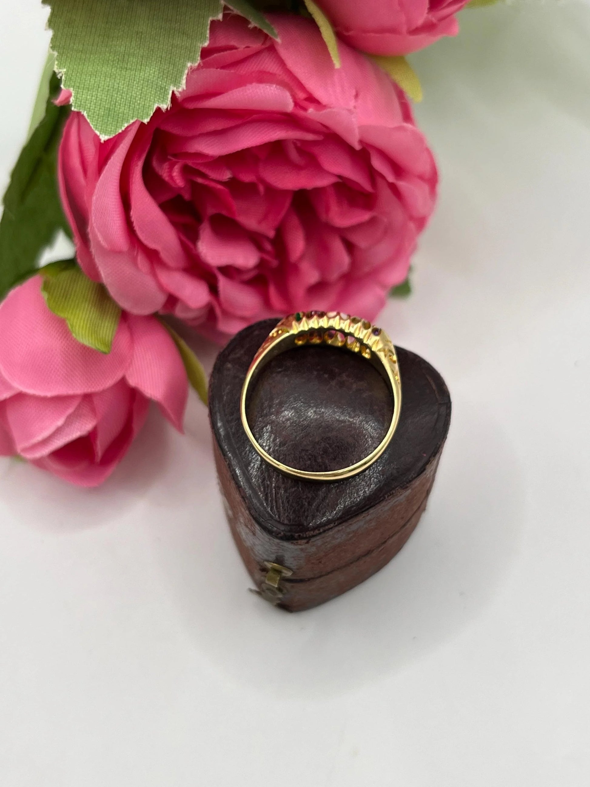 A five stone acrostic ADORE ring in yellow gold, in a heart-shaped ring box