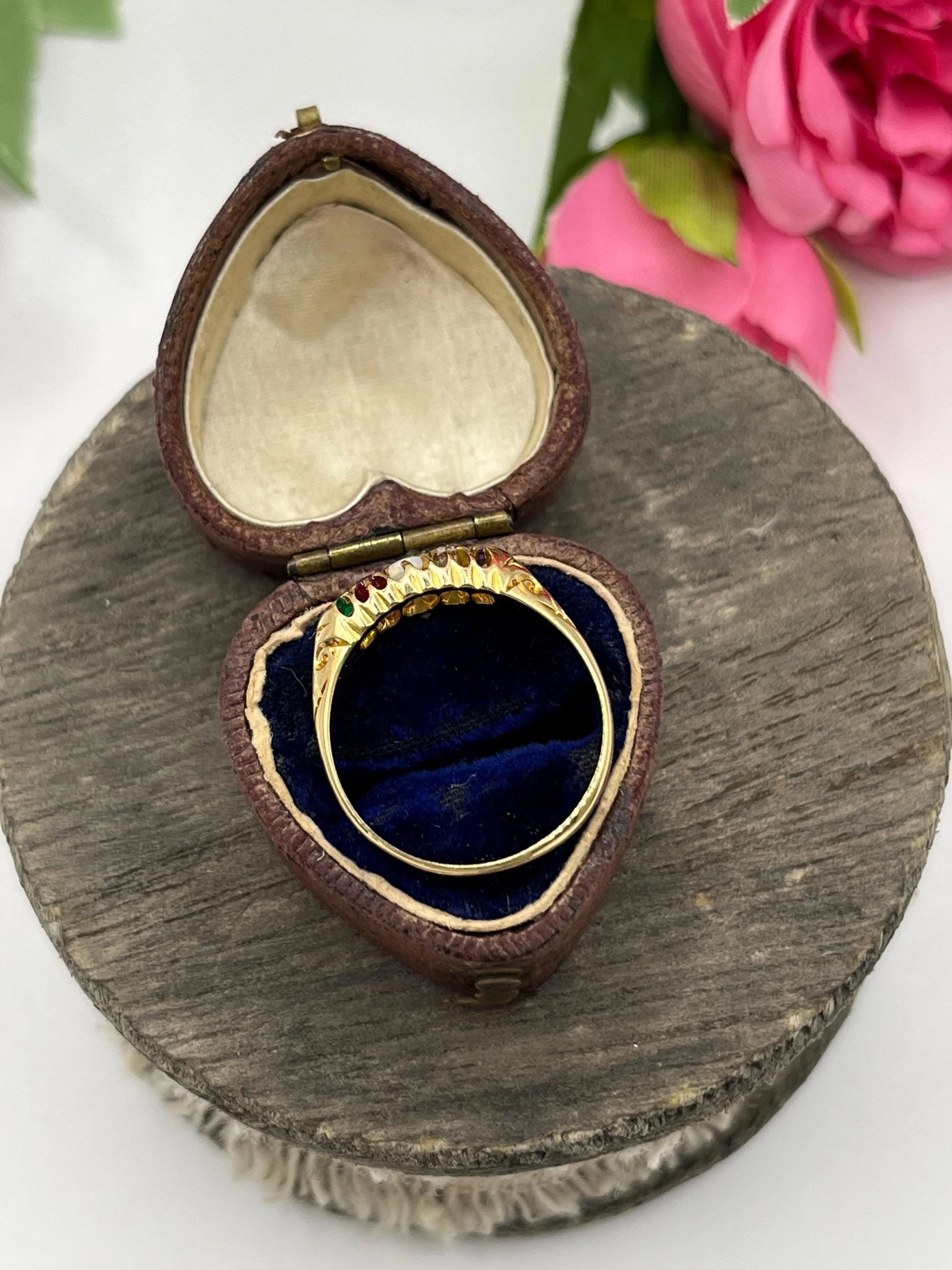 A five stone acrostic ADORE ring in yellow gold, in a heart-shaped ring box