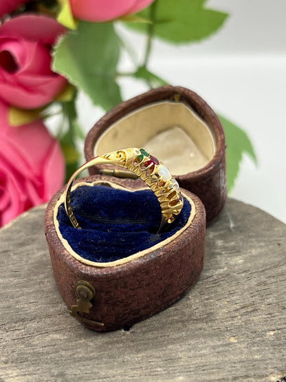 A five stone acrostic ADORE ring in yellow gold, in a heart-shaped ring box