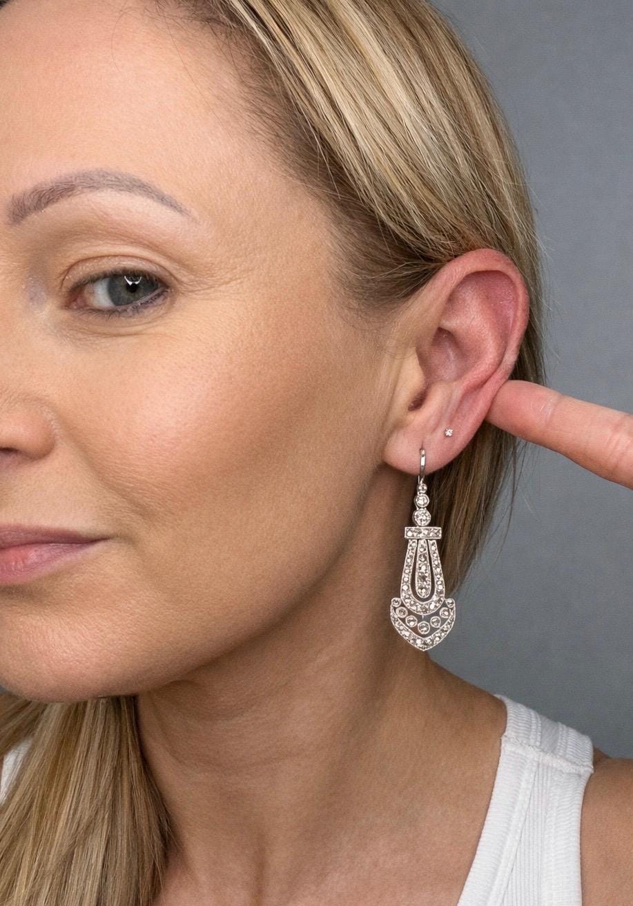 An antique platinum diamond drop earring, modelled in an ear