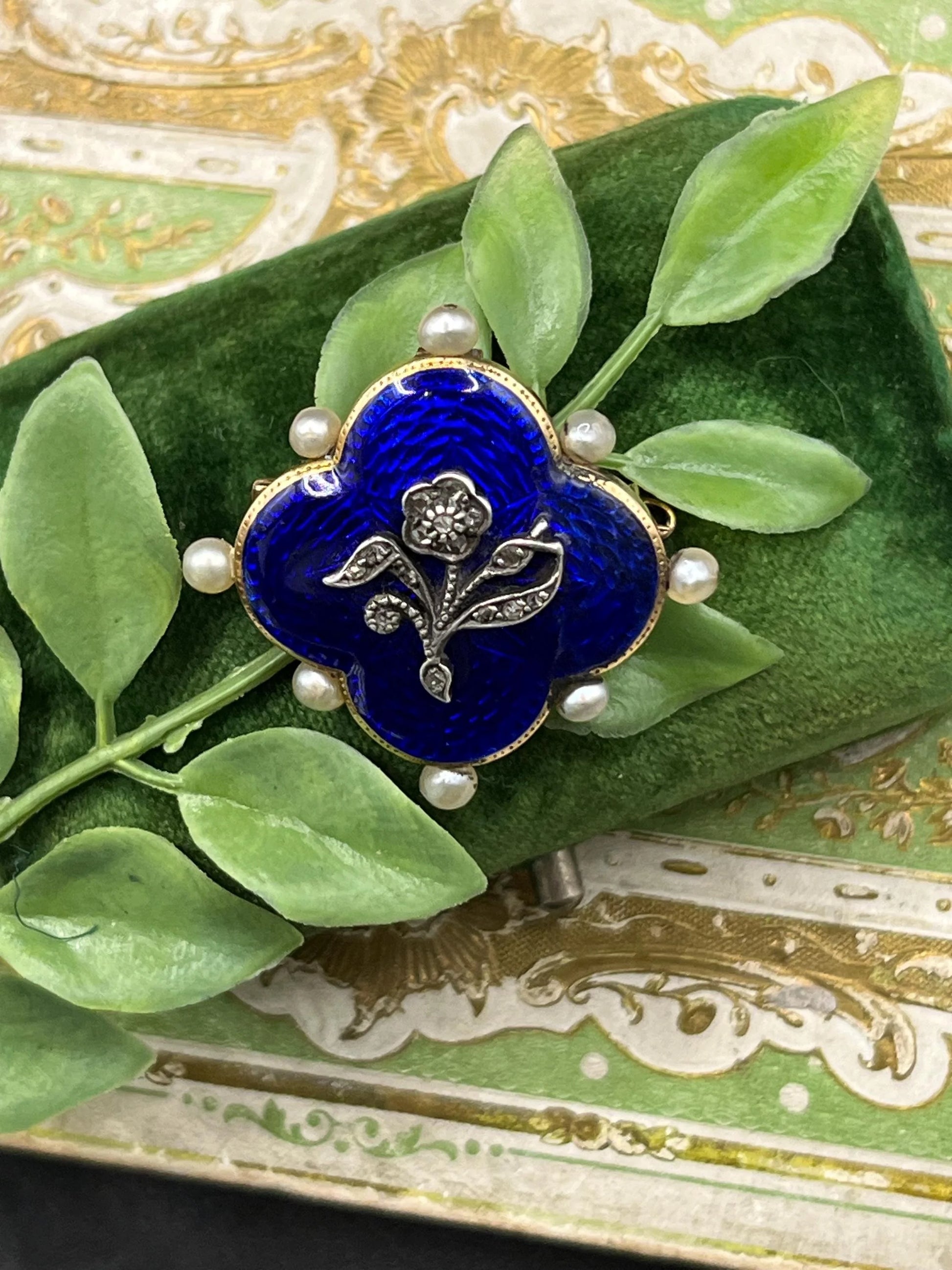 A diamond flower, blue enamel and pearl brooch in yellow gold