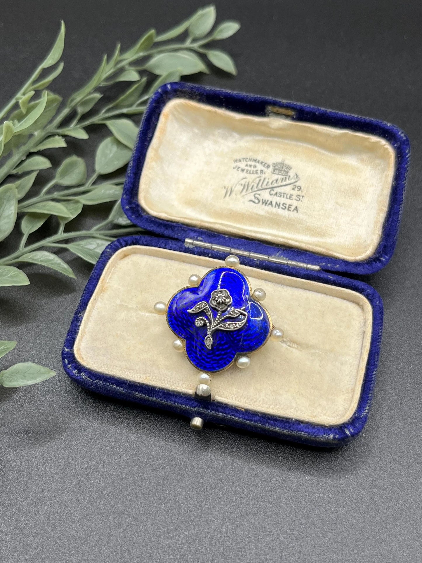 A diamond flower, blue enamel and pearl brooch in yellow gold, in an antique box