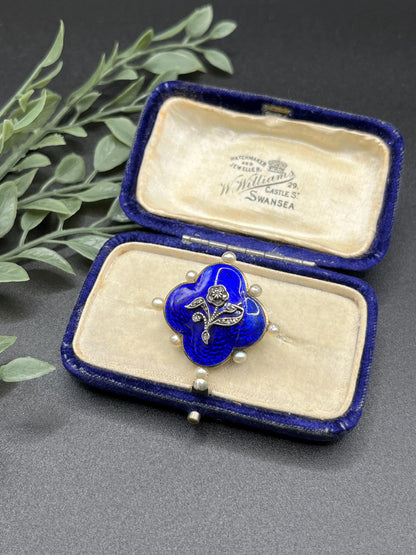 A diamond flower, blue enamel and pearl brooch in yellow gold, in an antique box