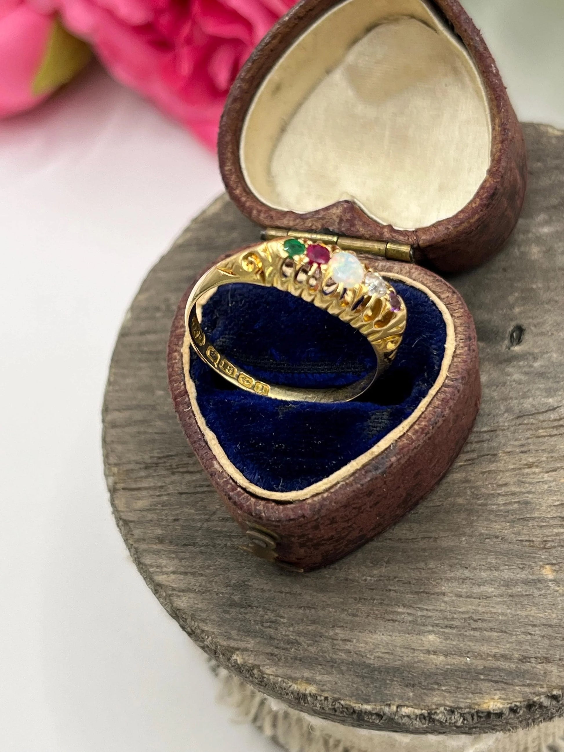 A five stone acrostic ADORE ring in yellow gold, in a heart-shaped ring box