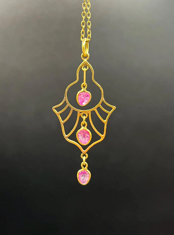 A yellow gold three stone ruby openwork drop pendant on a yellow gold chain