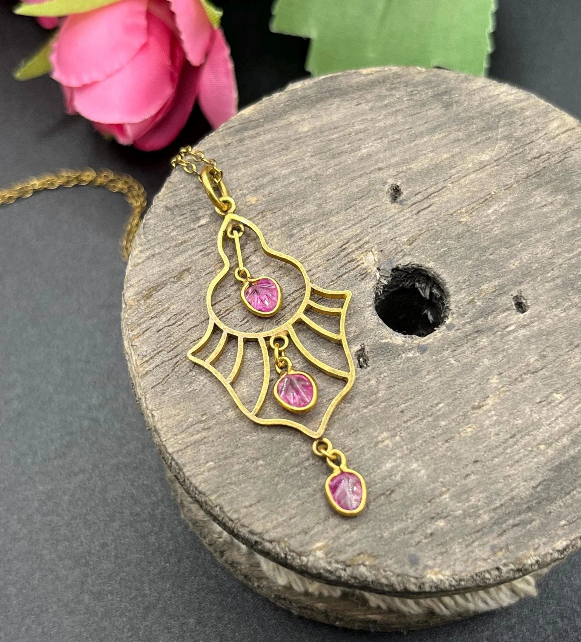 A yellow gold three stone ruby openwork drop pendant on a yellow gold chain