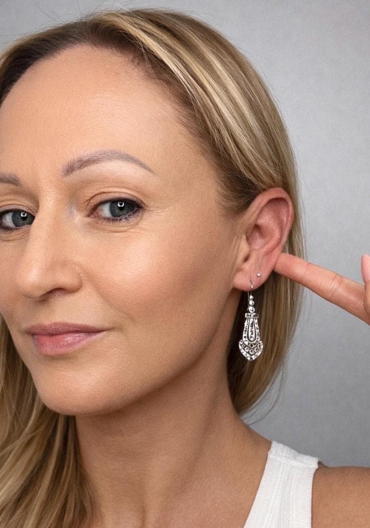 An antique platinum diamond drop earring, modelled in an ear