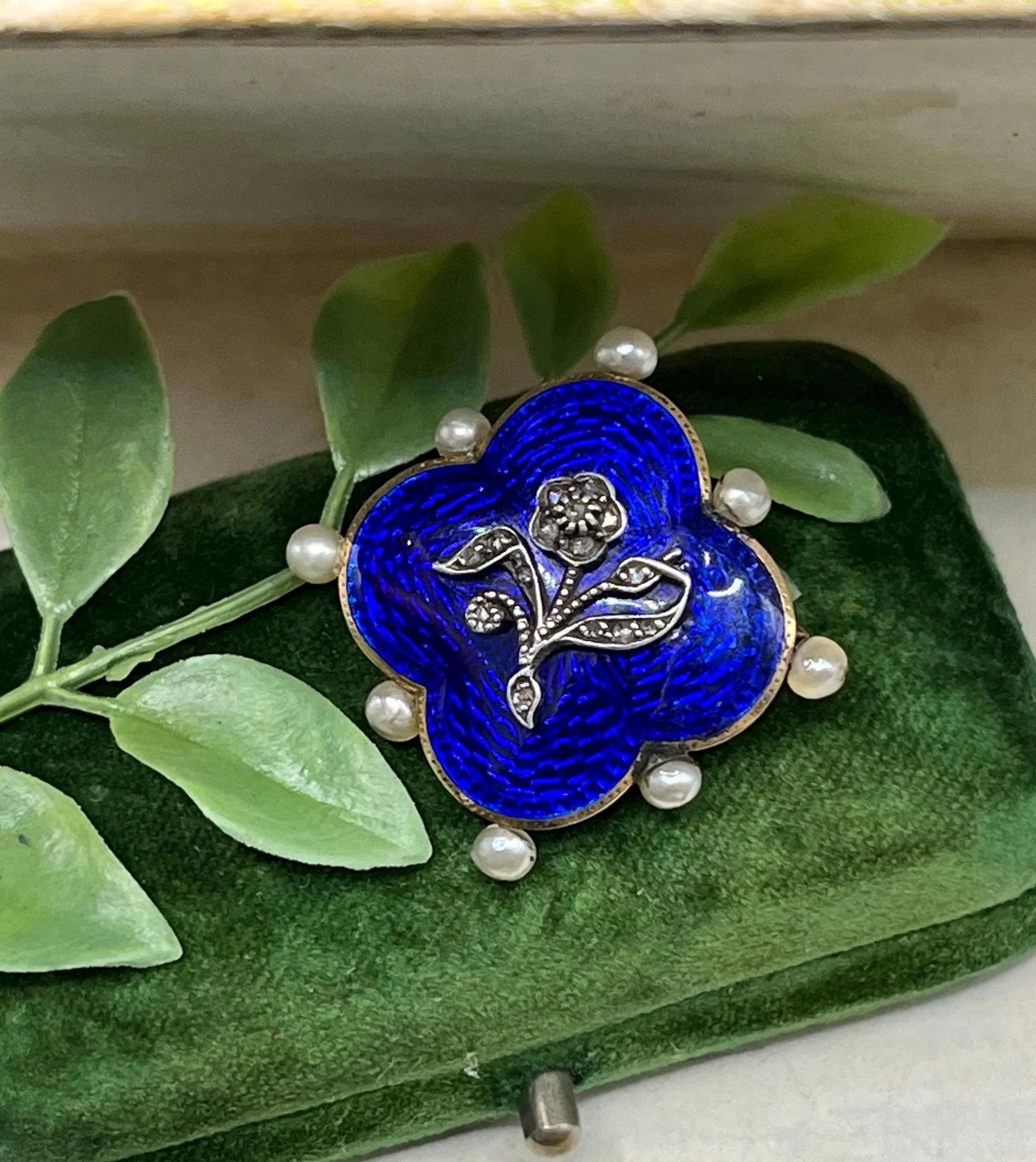 A diamond flower, blue enamel and pearl brooch in yellow gold