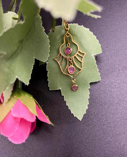 A yellow gold three stone ruby openwork drop pendant on a yellow gold chain