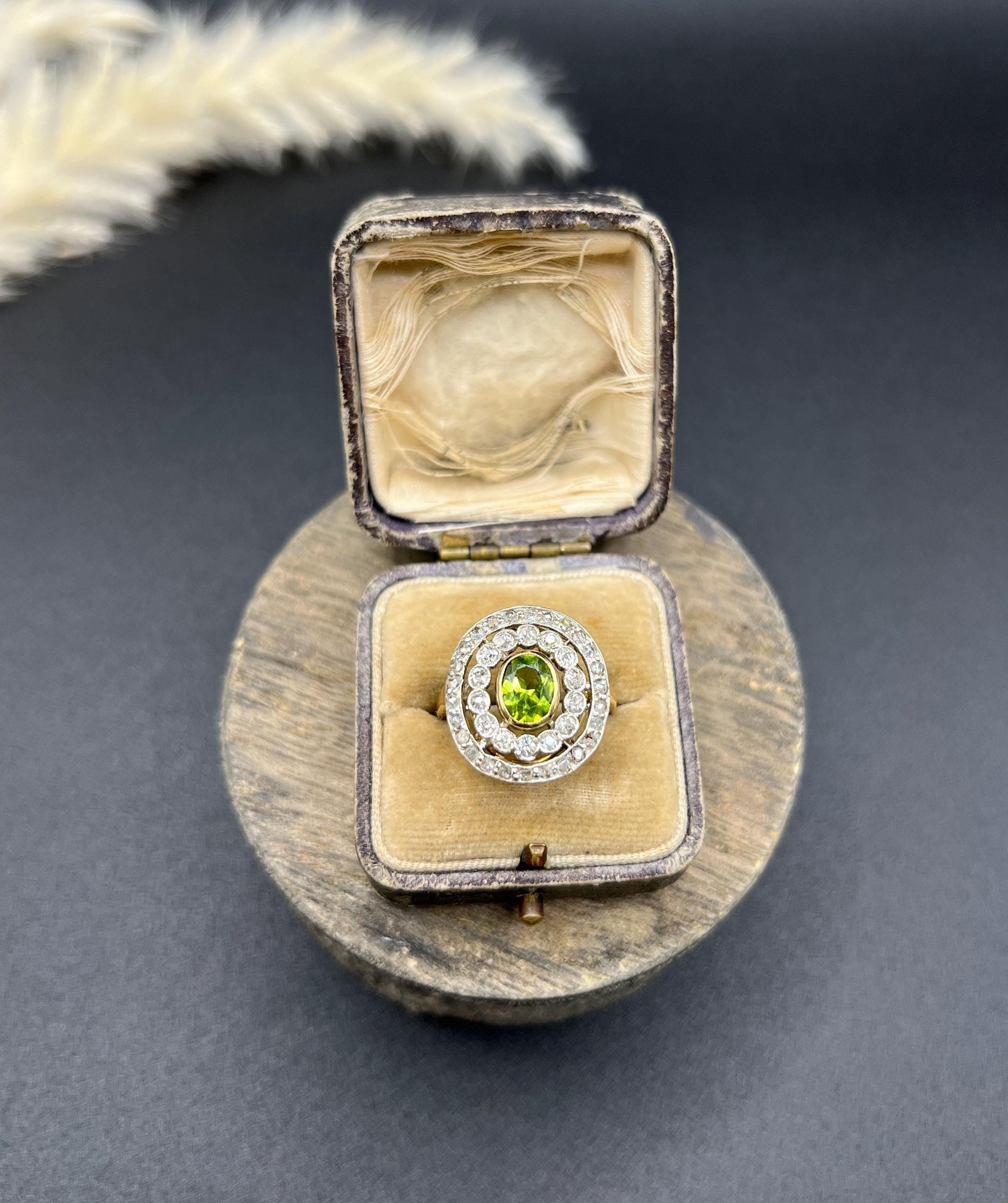 An oval peridot and old cut diamond fancy cluster ring in yellow gold and platinum, in a ring box