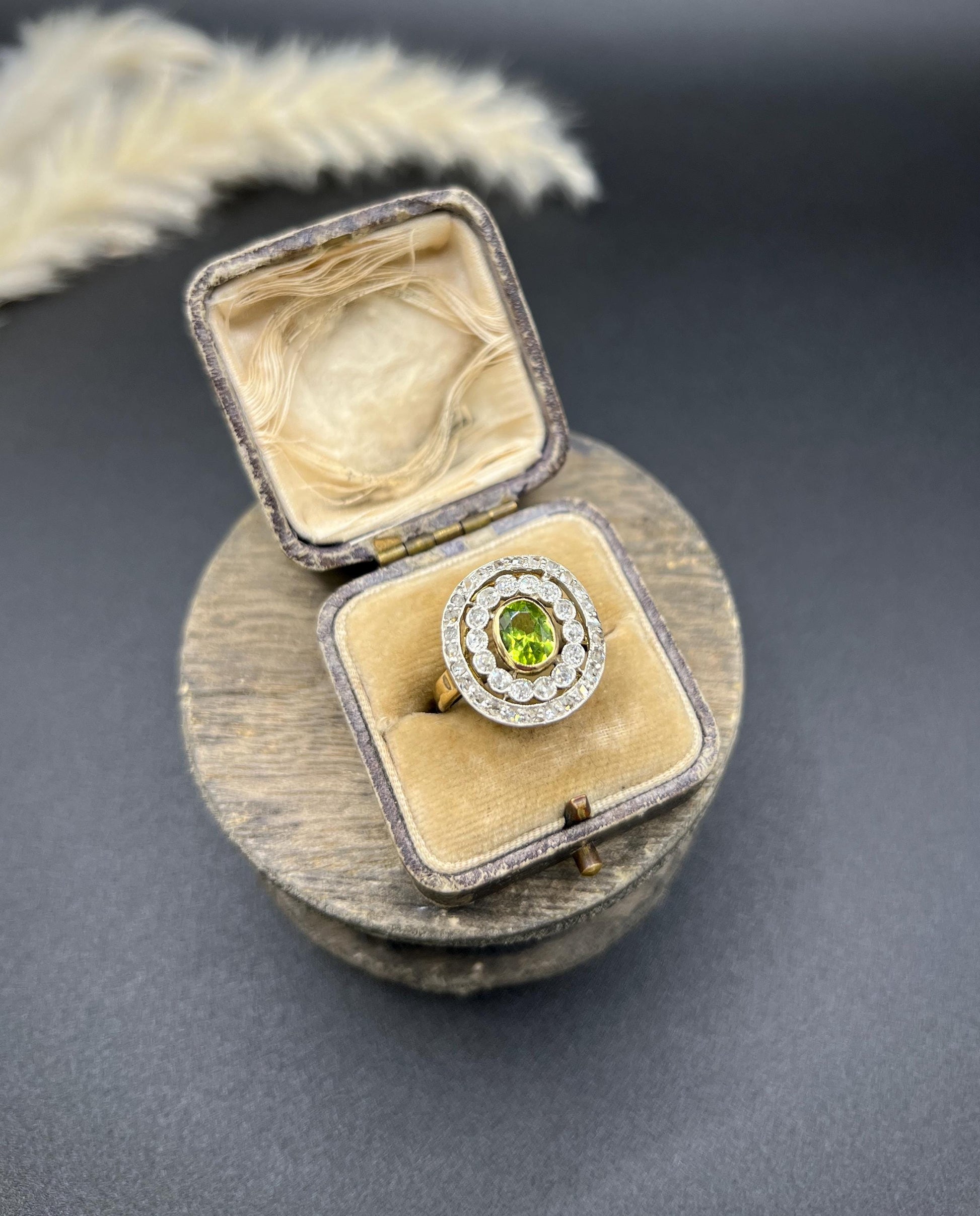 An oval peridot and old cut diamond fancy cluster ring in yellow gold and platinum, in a box