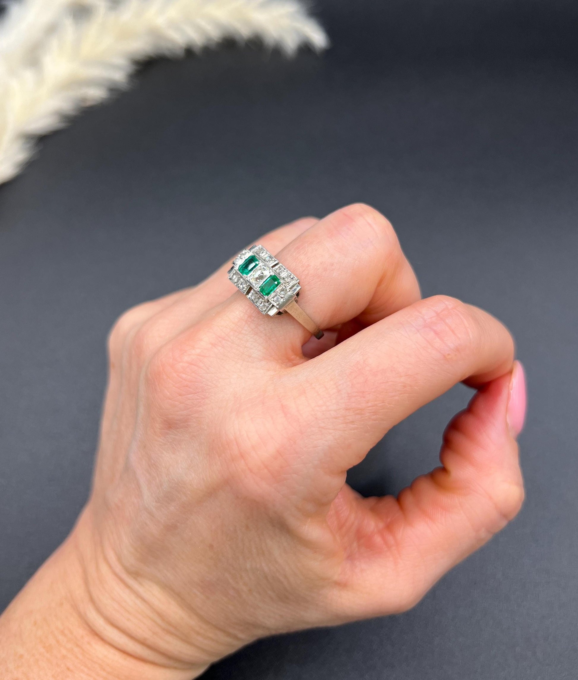 An emerald and old cut diamond rectangular ring in platinum, modelled on a hand