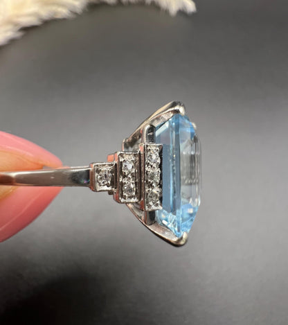 A large aquamarine and diamond dress ring in platinum, held in a hand