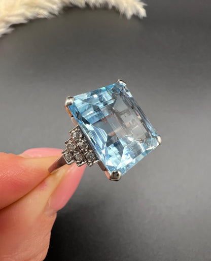 A large aquamarine and diamond dress ring in platinum, held in a hand