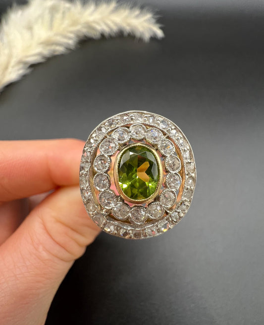 An oval peridot and old cut diamond fancy cluster ring in yellow gold and platinum