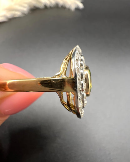 An oval peridot and old cut diamond fancy cluster ring in yellow gold and platinum