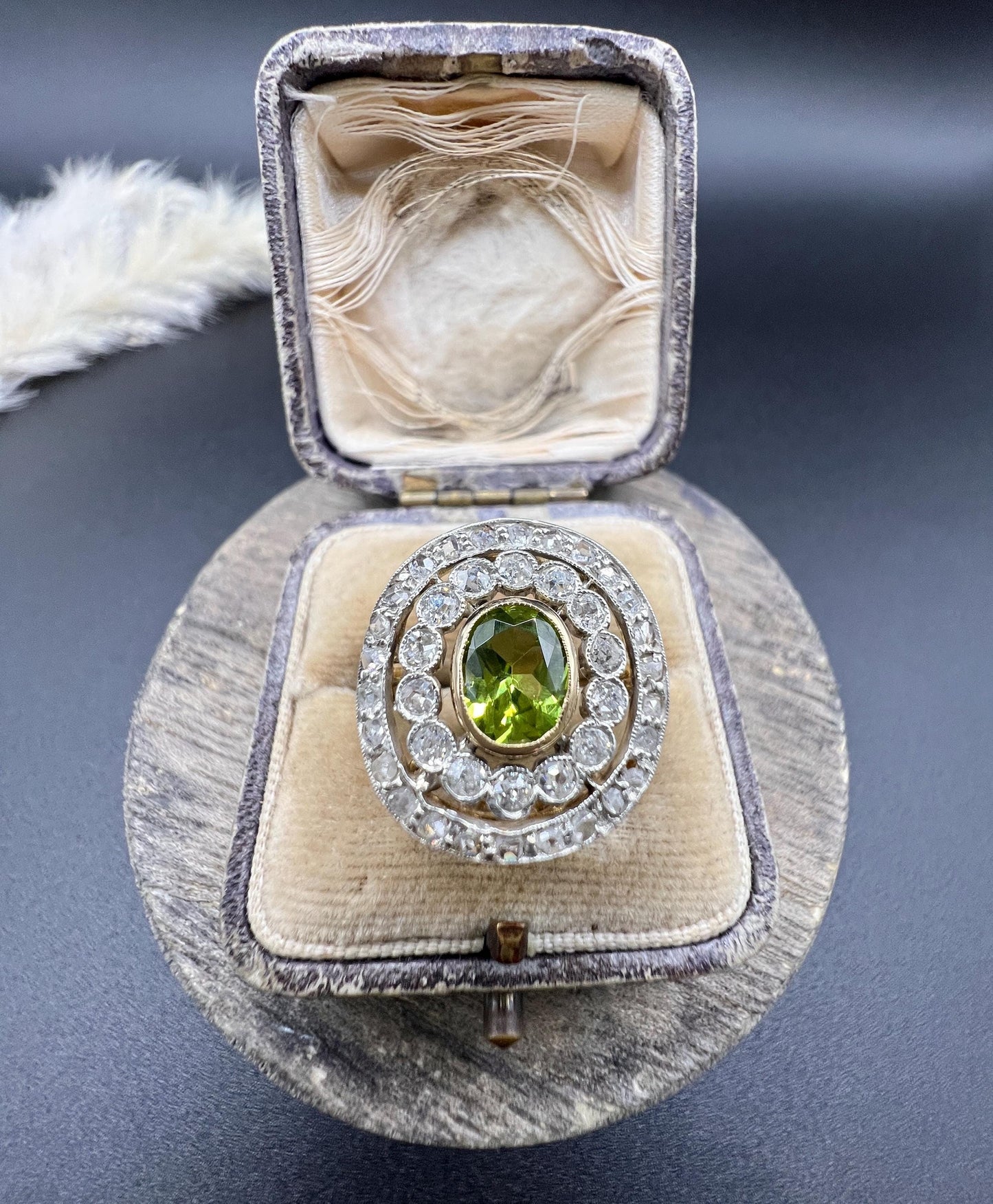 An oval peridot and old cut diamond fancy cluster ring in yellow gold and platinum, in a ring box