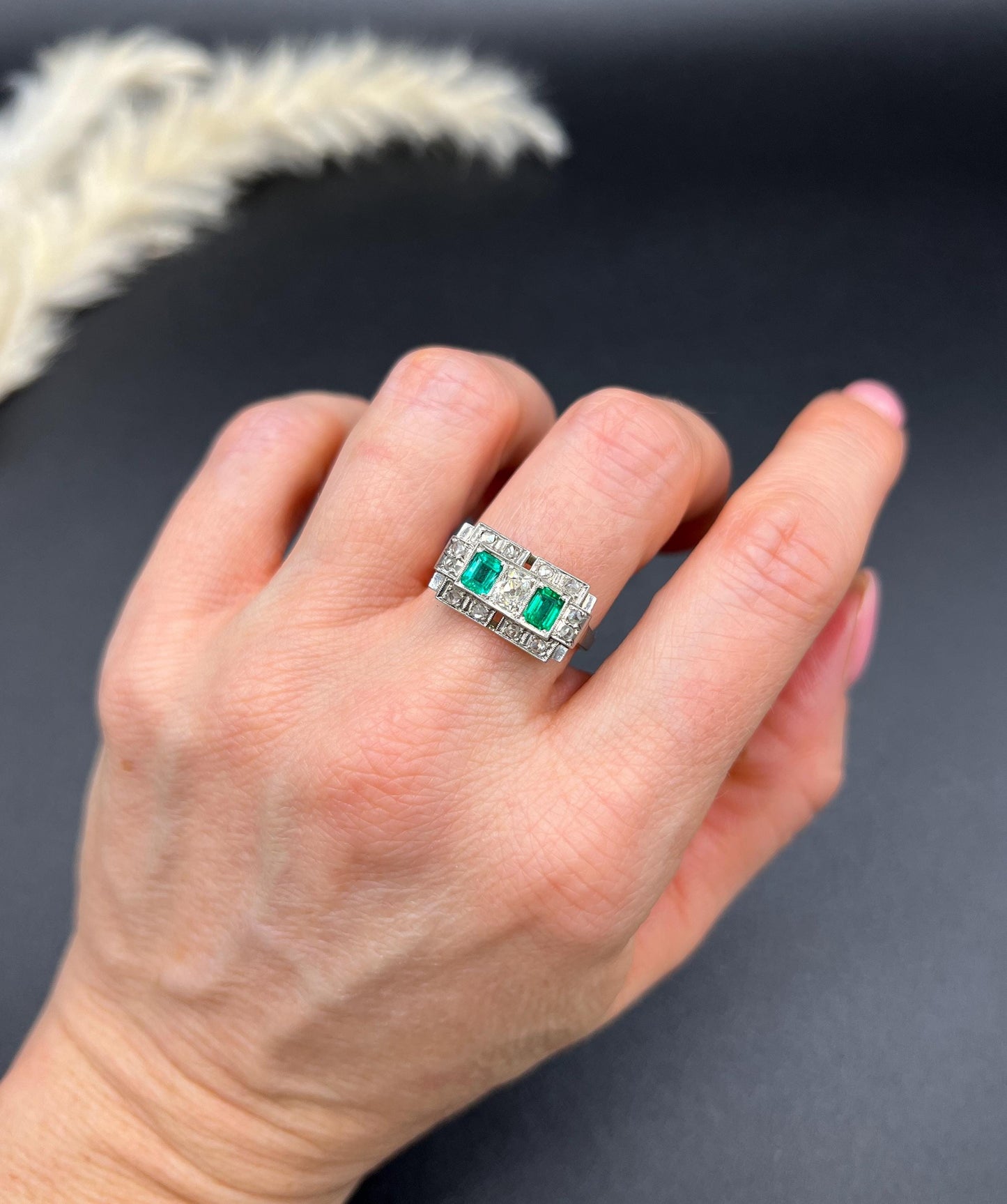 An emerald and old cut diamond rectangular ring in platinum, modelled on a hand