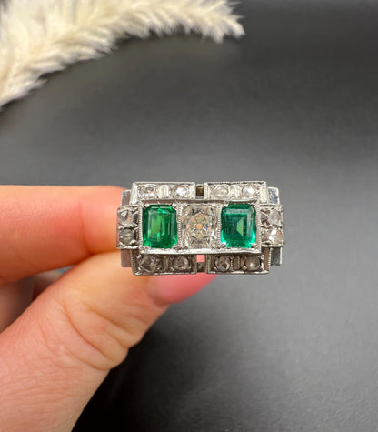 An emerald and old cut diamond rectangular ring in platinum, held in a hand