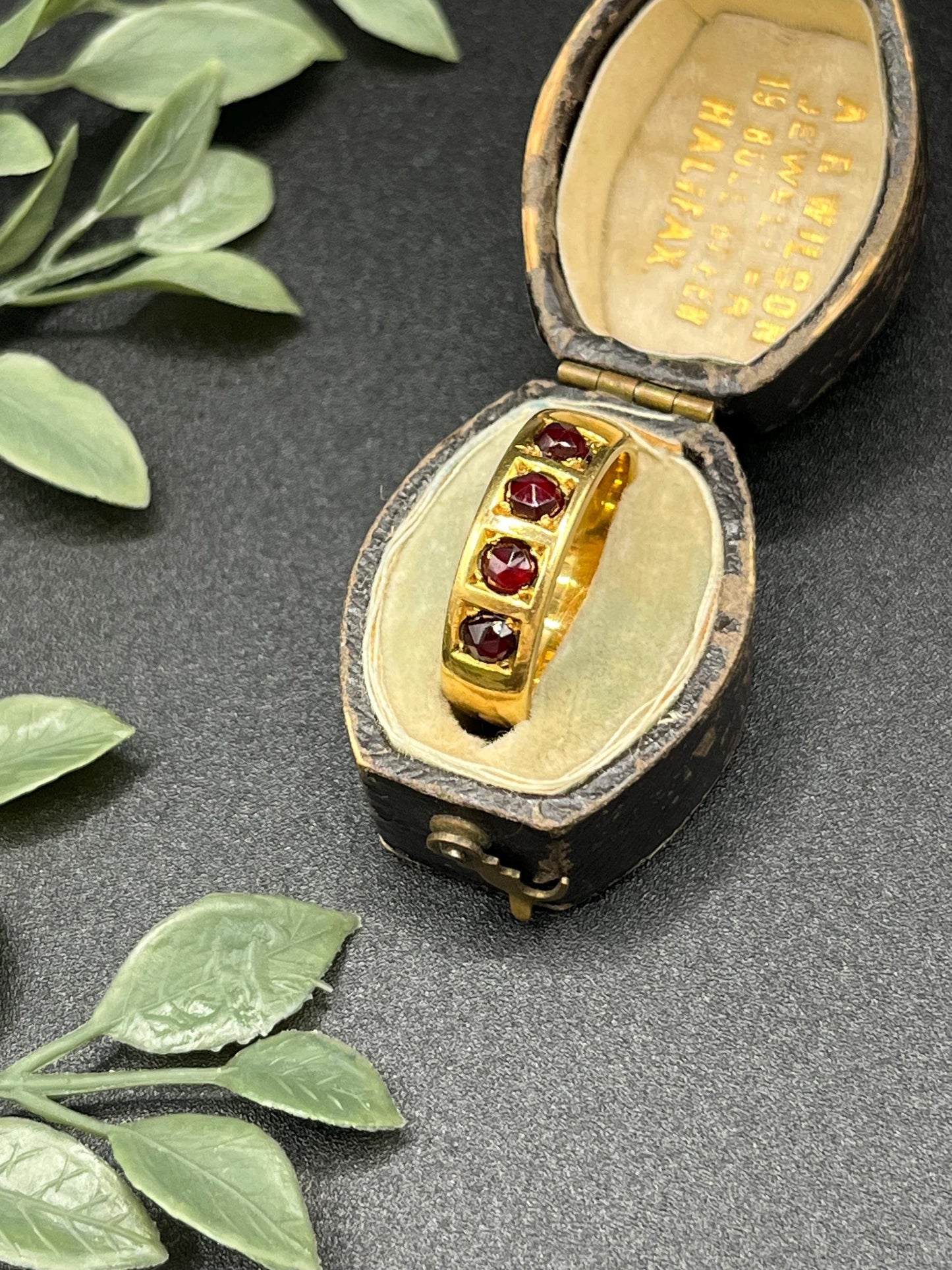 A yellow gold four stone garnet band ring, in an antique ring box
