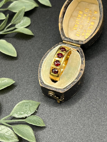 A yellow gold four stone garnet band ring, in an antique ring box