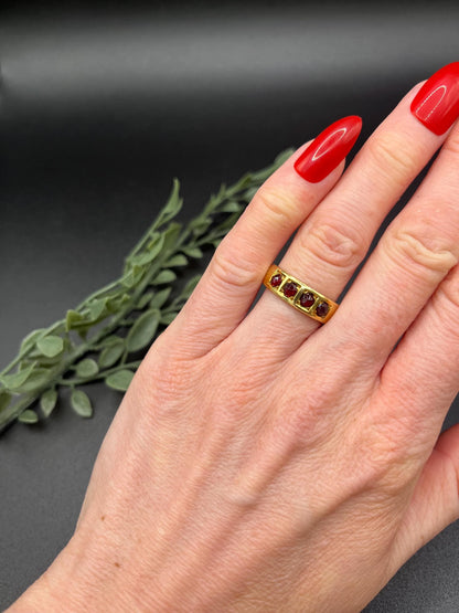 A yellow gold four stone garnet band ring, modelled on a hand