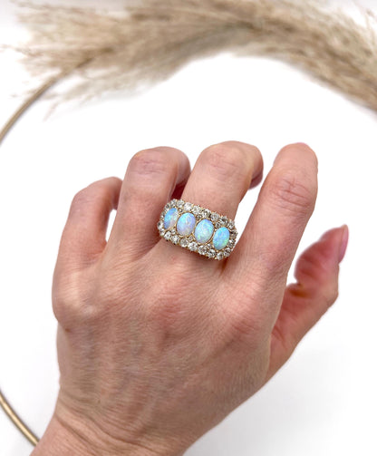 An antique oval opal and old cut diamond cluster row ring in yellow gold, modelled on a hand