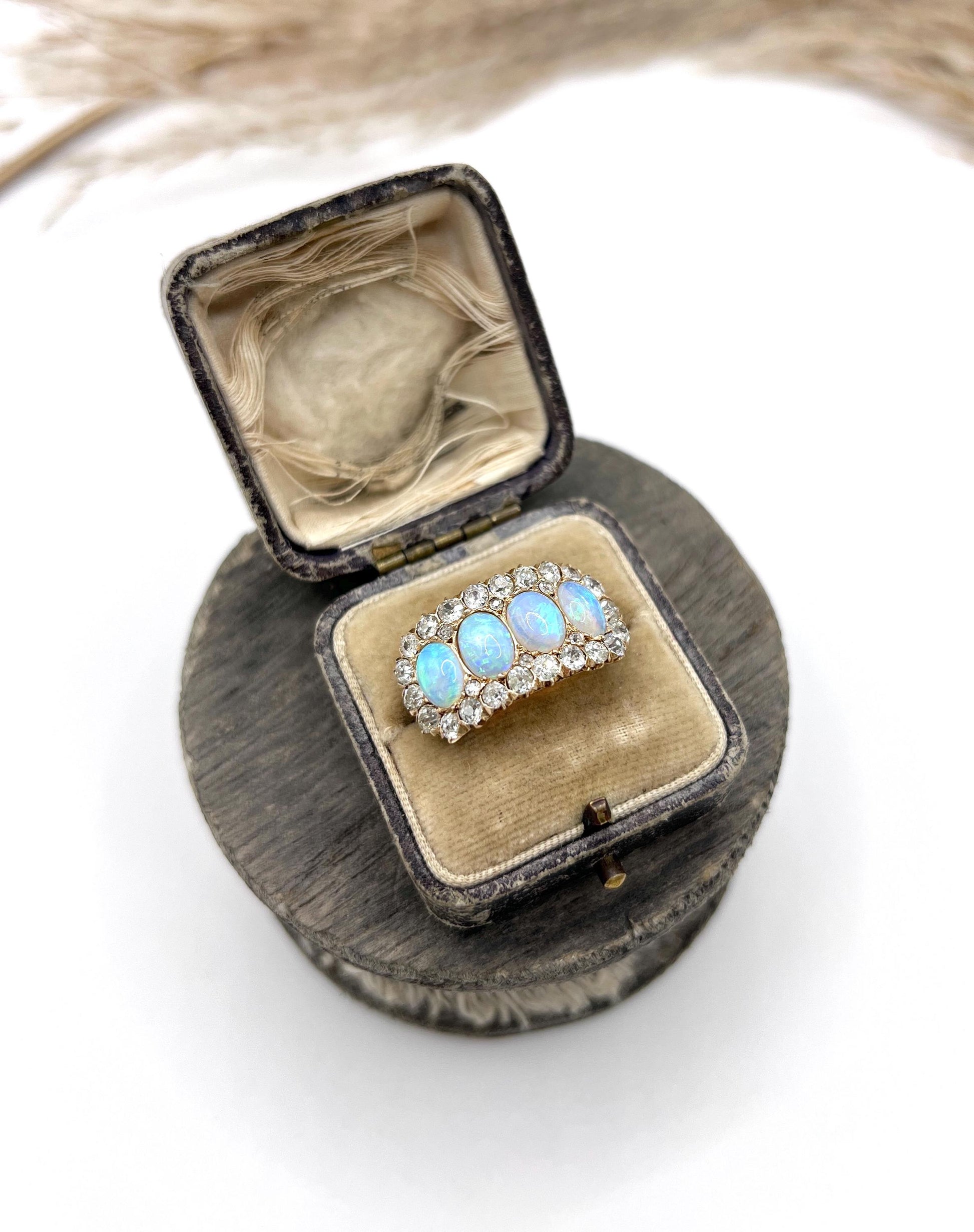 An antique oval opal and old cut diamond cluster row ring in yellow gold, in a box