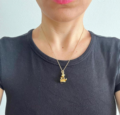 A yellow gold faith, hope and charity fob, with a heart-shaped bloodstone base, with a chain, modelled by a woman wearing a black top