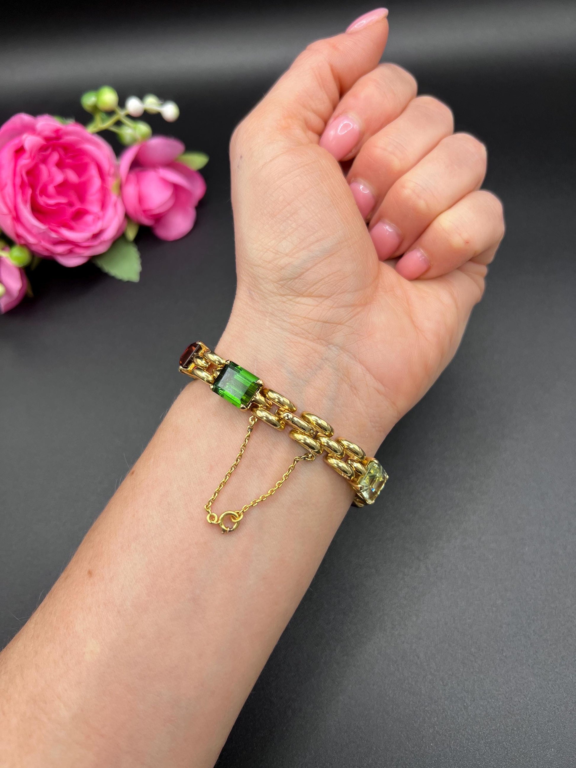 An emerald cut multi-gemstone bracelet in yellow gold, modelled on a wrist