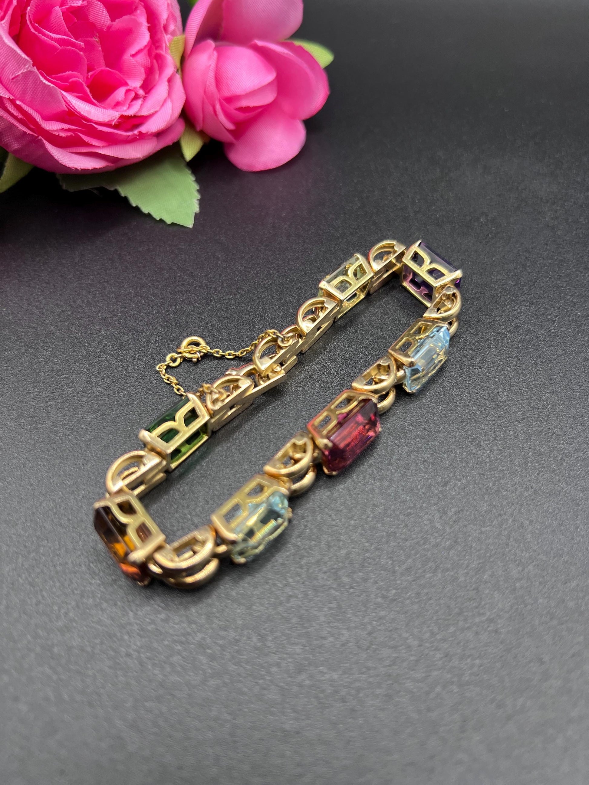 An emerald cut multi-gemstone bracelet in yellow gold