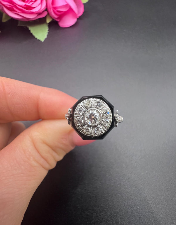 A platinum, black onyx and diamond fancy cocktail cluster ring, held in a hand