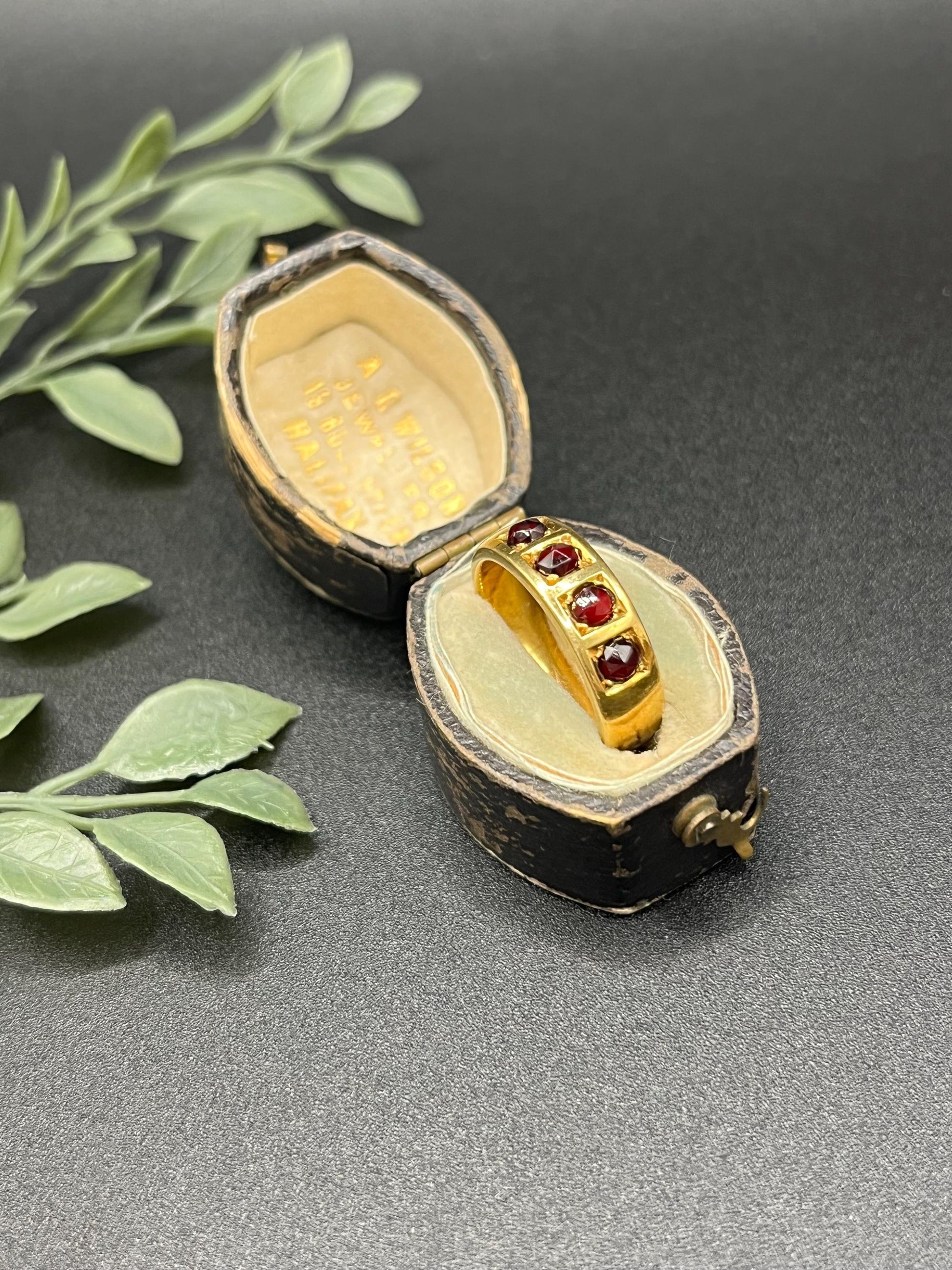 A yellow gold four stone garnet band ring, in an antique ring box