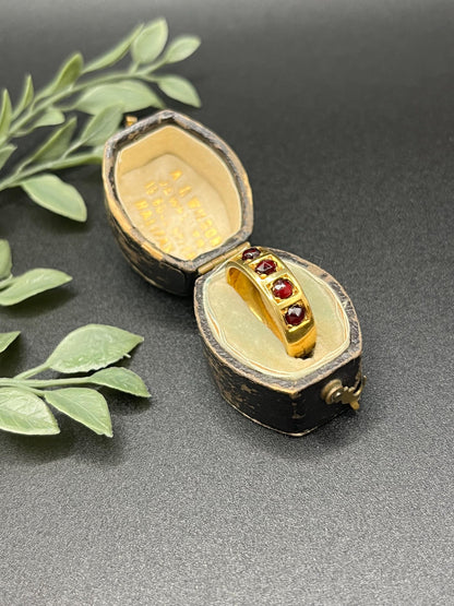A yellow gold four stone garnet band ring, in an antique ring box